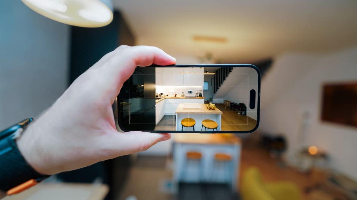 A smartphone in focus capturing a modern kitchen interior, showcasing real estate potential.