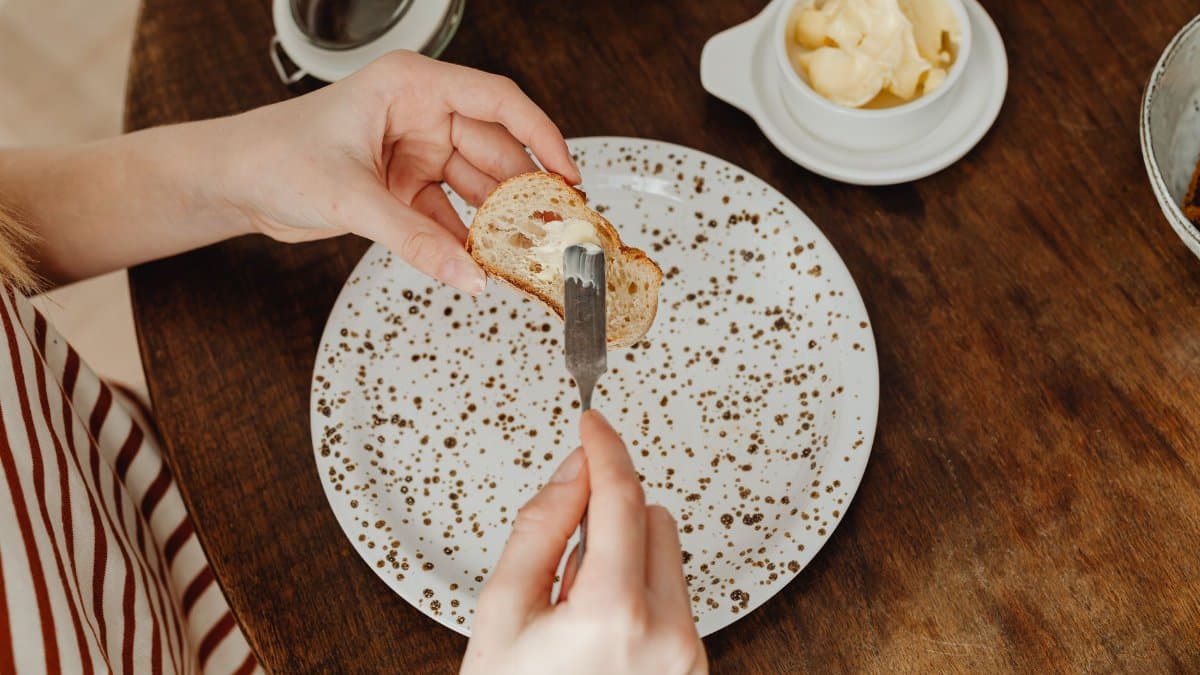 Close-up of a person spreading butter on bread for a delicious breakfast.