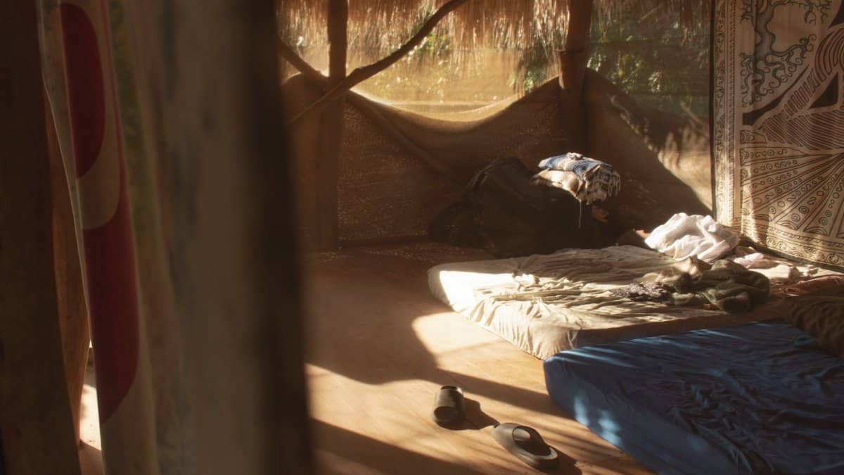 Sunlit rustic cabin interior featuring minimal bedding and woven decorations.