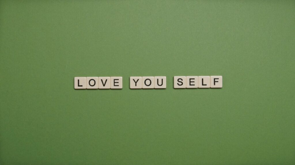 Positive message 'Love You Self' spelled with letter tiles on green background.