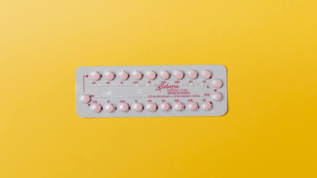 Close-up of a blister pack of pink pills on a vivid yellow background for medication concept.