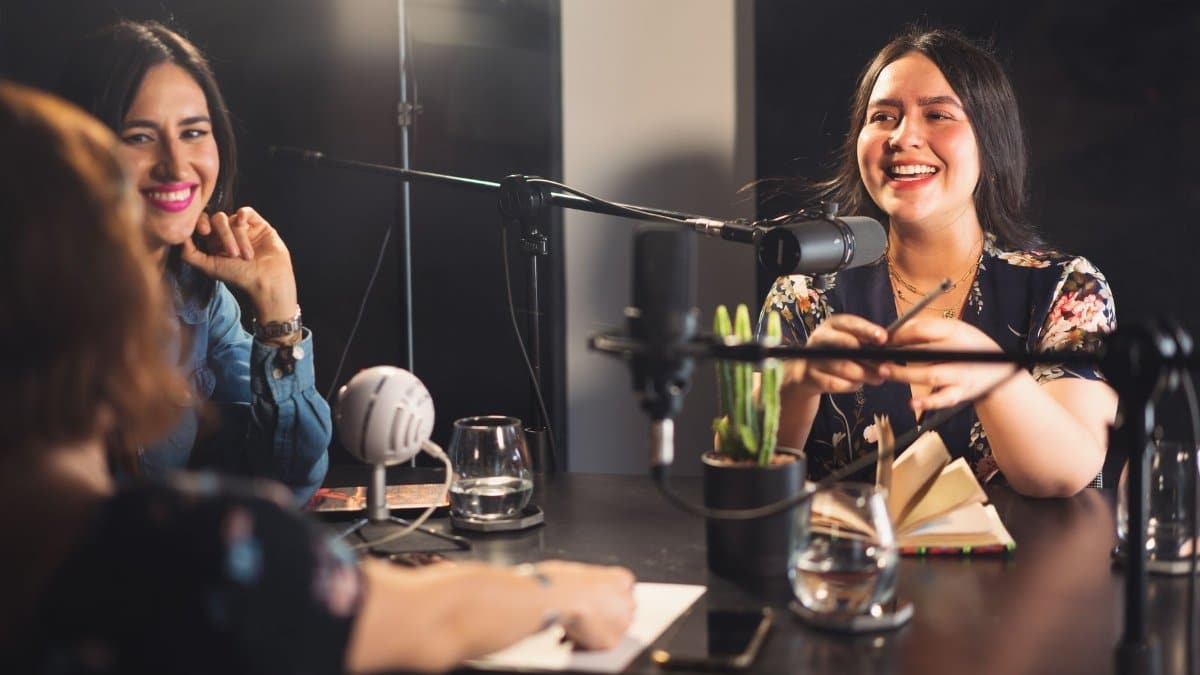 Three women enjoying a lively podcast recording session in a modern studio.