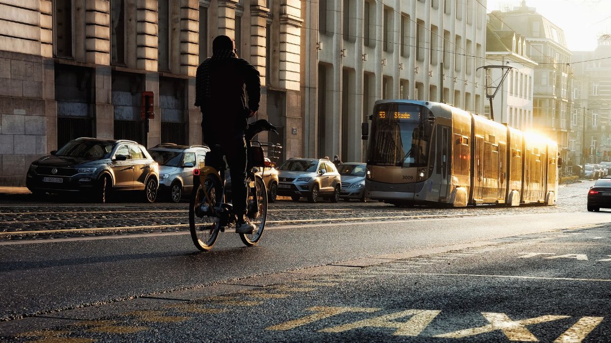 A cyclist and tram in motion on a sunny street in Brussels, reflecting urban life.