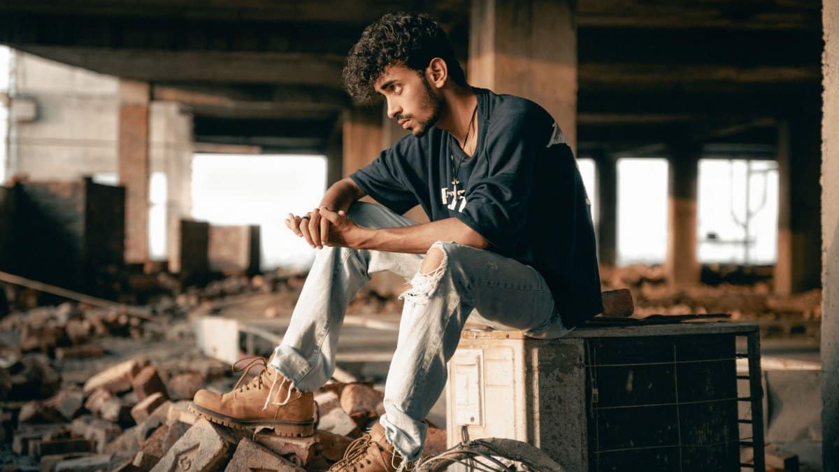 Young man sitting thoughtfully in an unfinished urban environment.