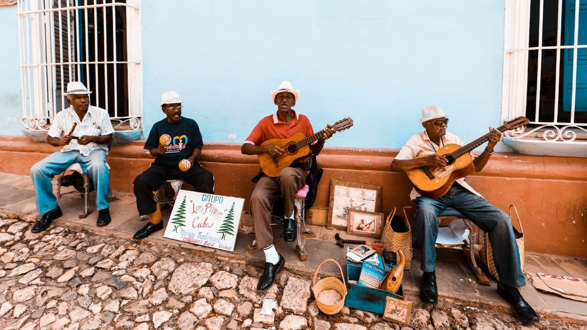 A group of elderly men playing guitars and maracas on a Cuban street, showcasing traditional music.