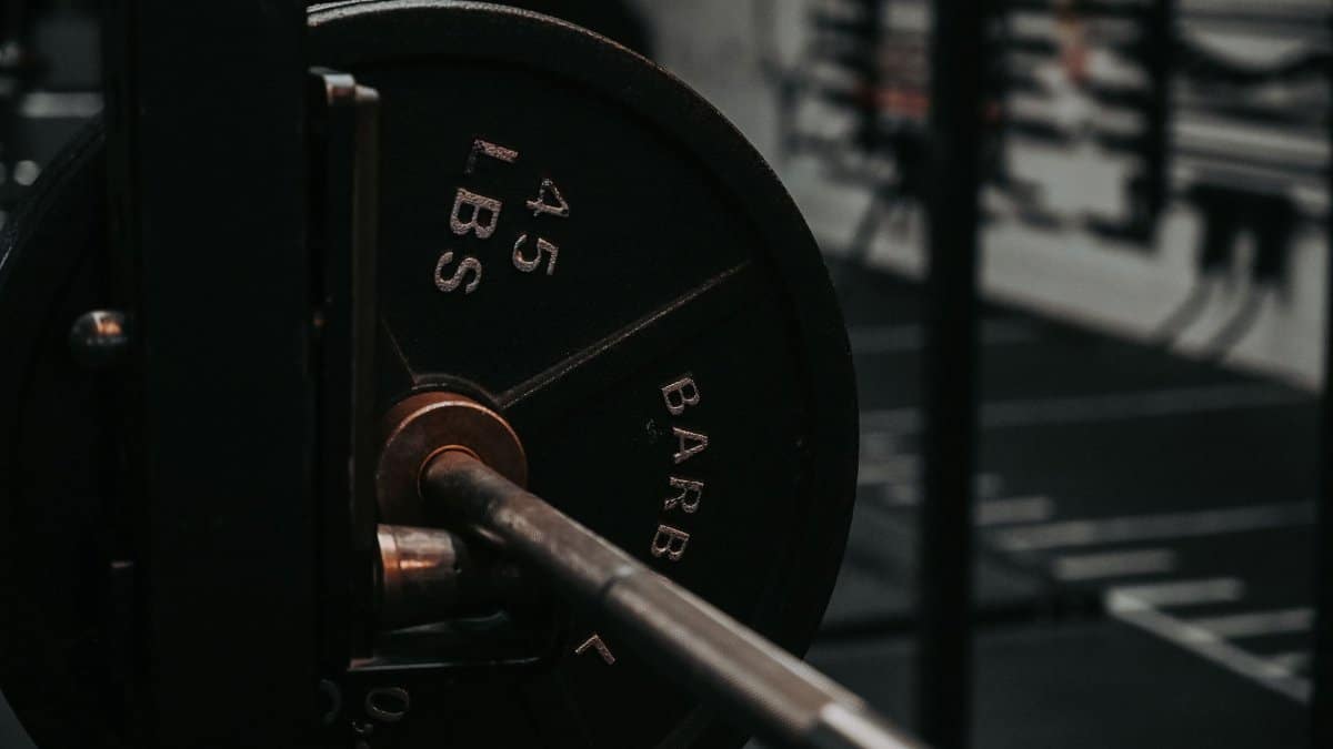 Detailed close-up of a heavy barbell loaded with a 45 lbs weight plate in a gym setting.