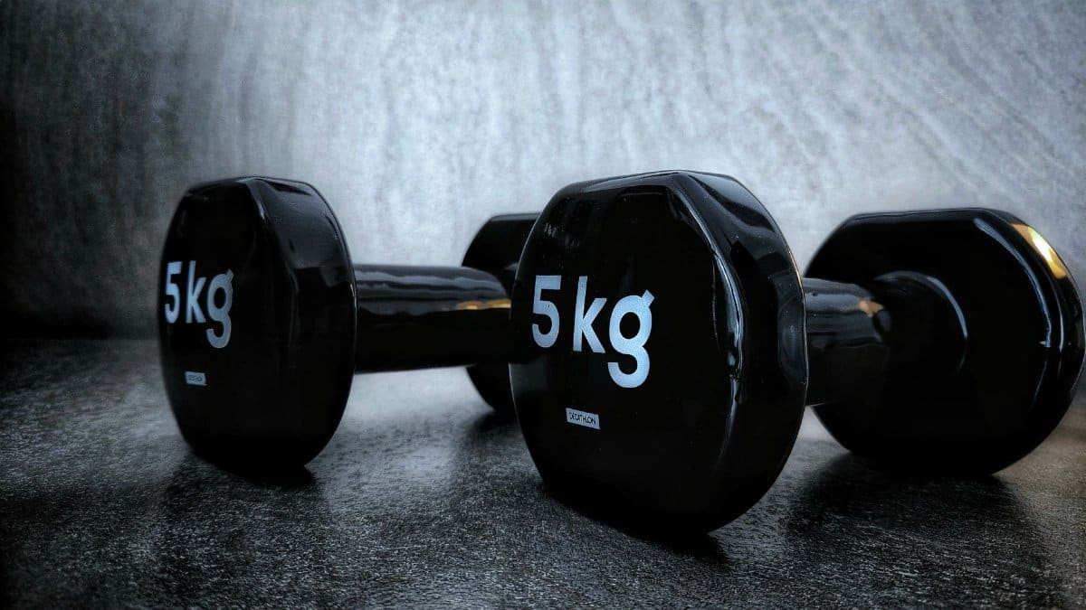 Black 5kg dumbbells on a dark background, perfect for fitness and weight training concepts.