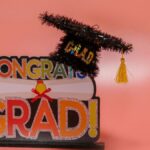 Celebratory 'Congrats Grad' sign with a glittery graduation cap on pink background.