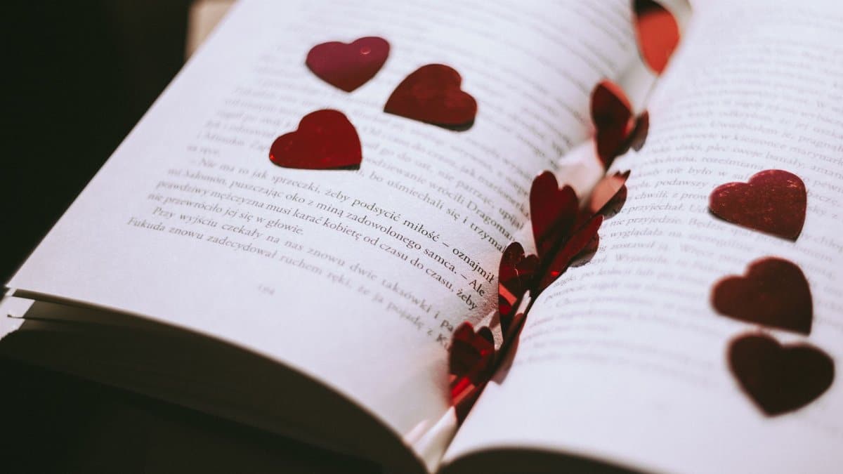 An open book adorned with red heart-shaped confetti, perfect for Valentine's or romantic themes.
