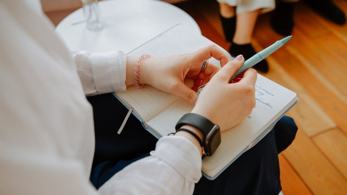 Close-up of a person taking notes during a therapy session, highlighting mental health focus.