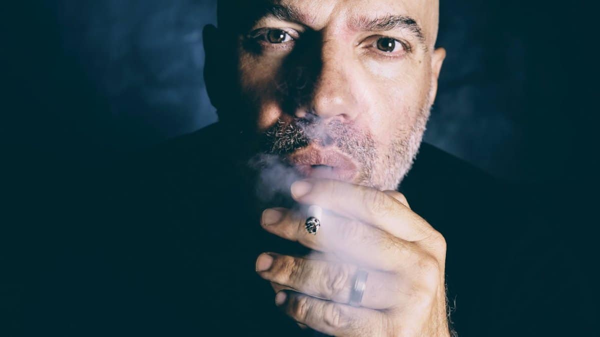 Close-up portrait of a man smoking, emphasizing addiction themes.