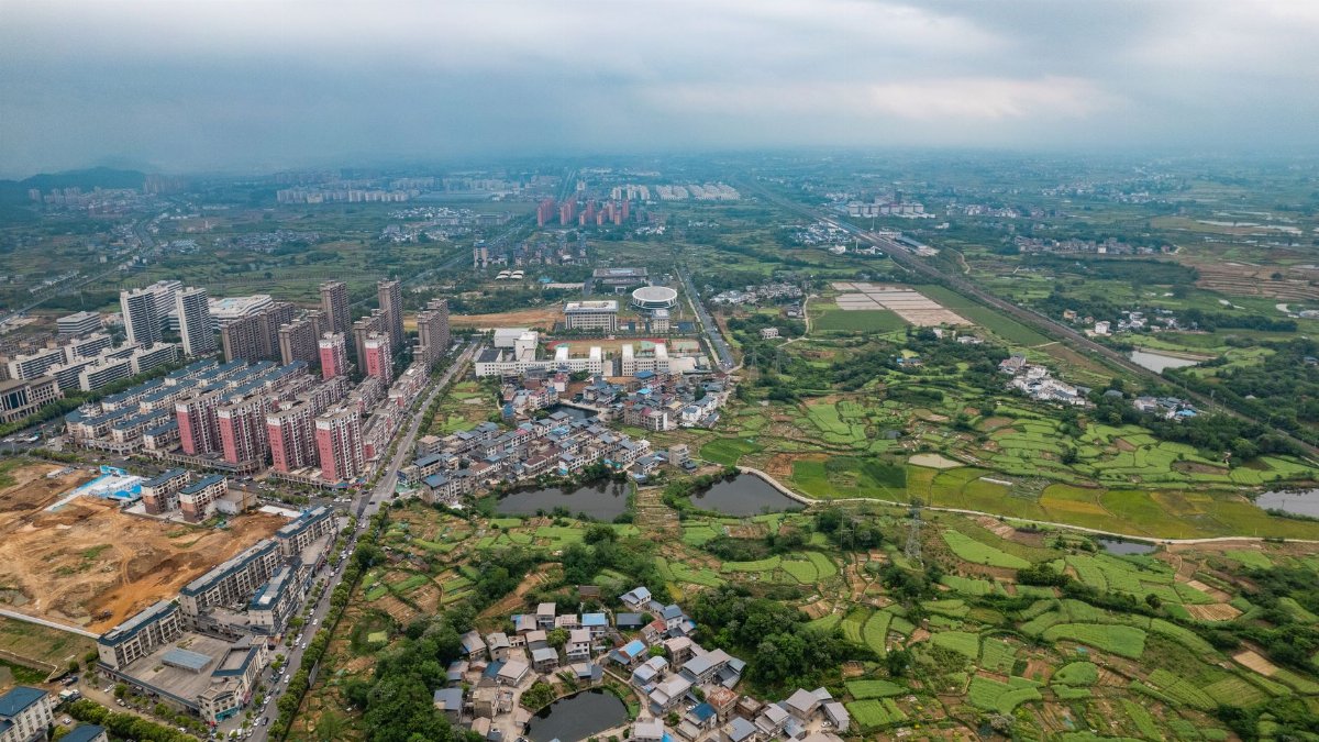 Aerial view of Luoding City with its urban and rural landscape under a cloudy sky.