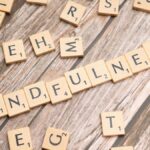 Wooden letter tiles spelling 'mindfulness' on a rustic wood background.