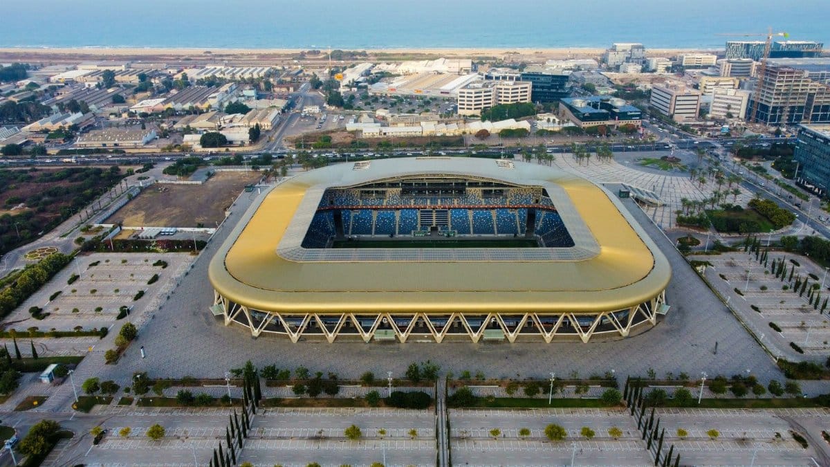 Aerial shot of a modern stadium near the coast with parking area.