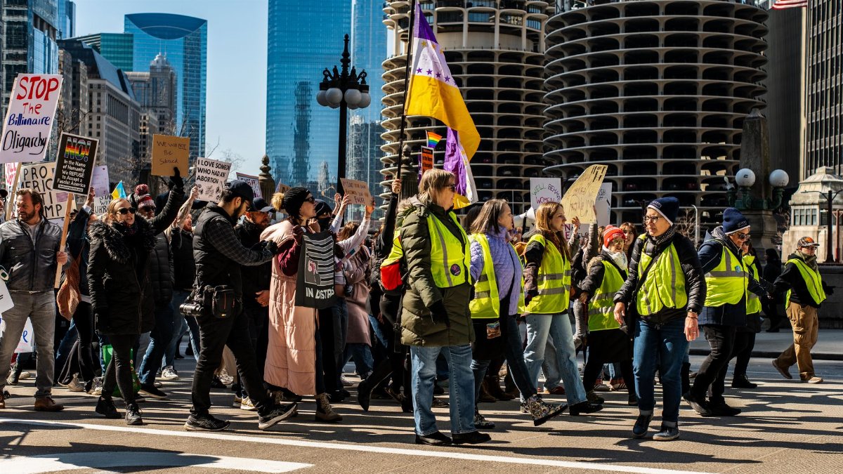 Large group of diverse protesters marching in downtown Chicago, advocating for various social causes.