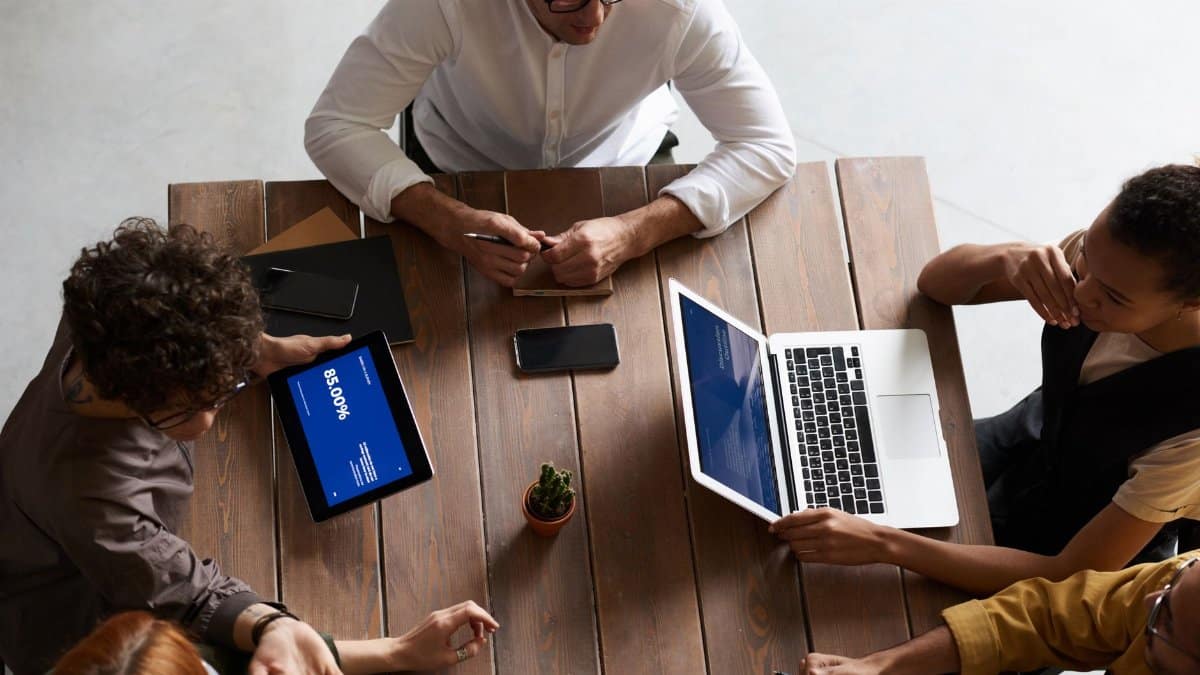 Top view of a diverse team collaborating with laptops and tablets in a modern workspace.