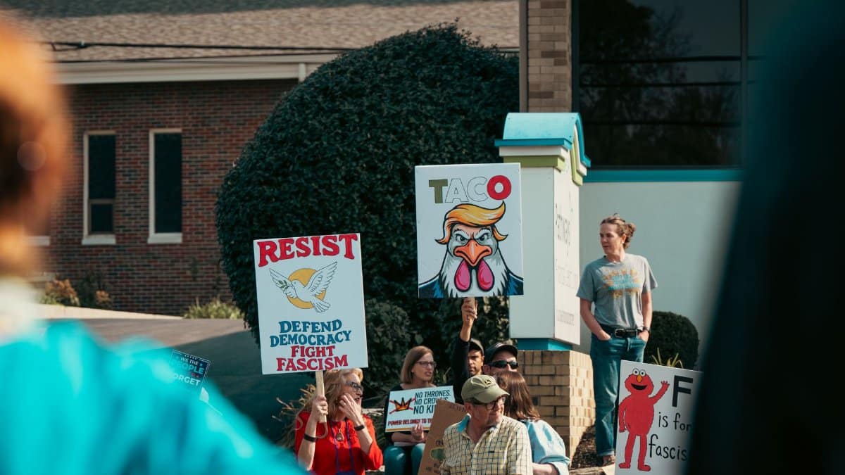 Group protesting with signs promoting democracy and anti-fascism outside a building.