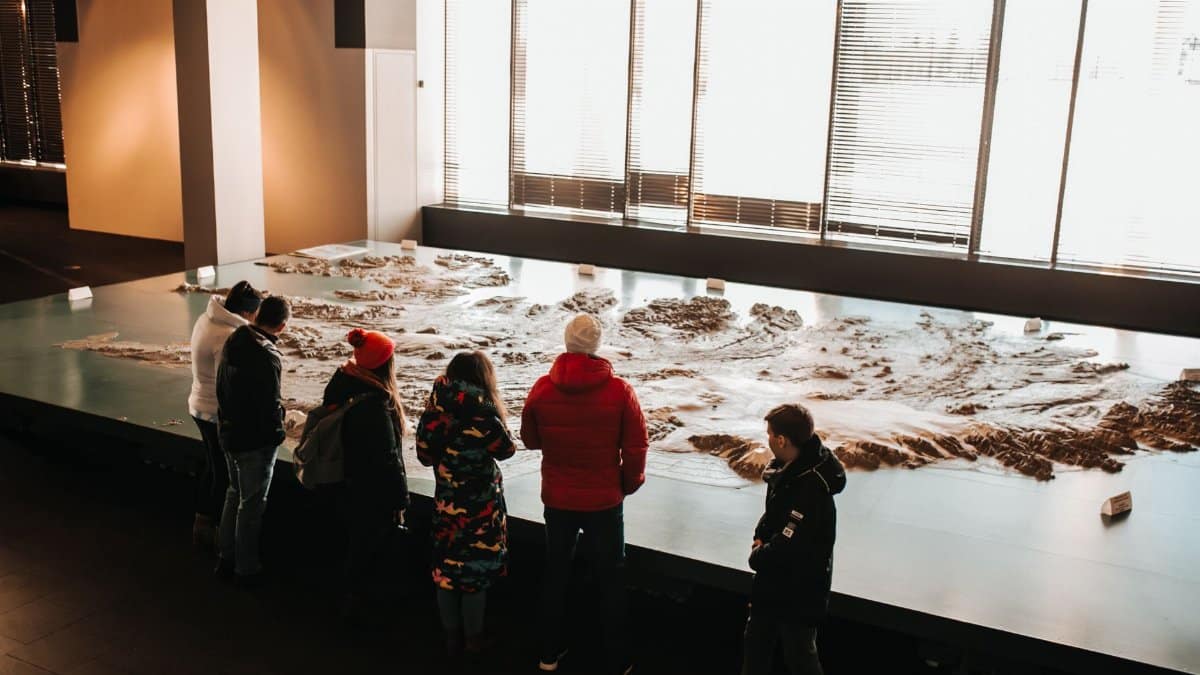 Group of adults exploring a large map exhibit in a museum setting during winter.