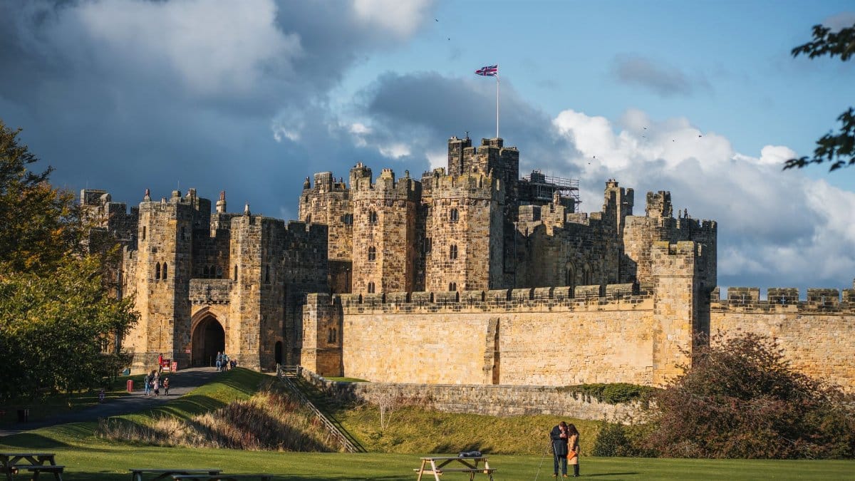 Explore the historic Alnwick Castle in England, captured under a stunning sky with autumn hues.
