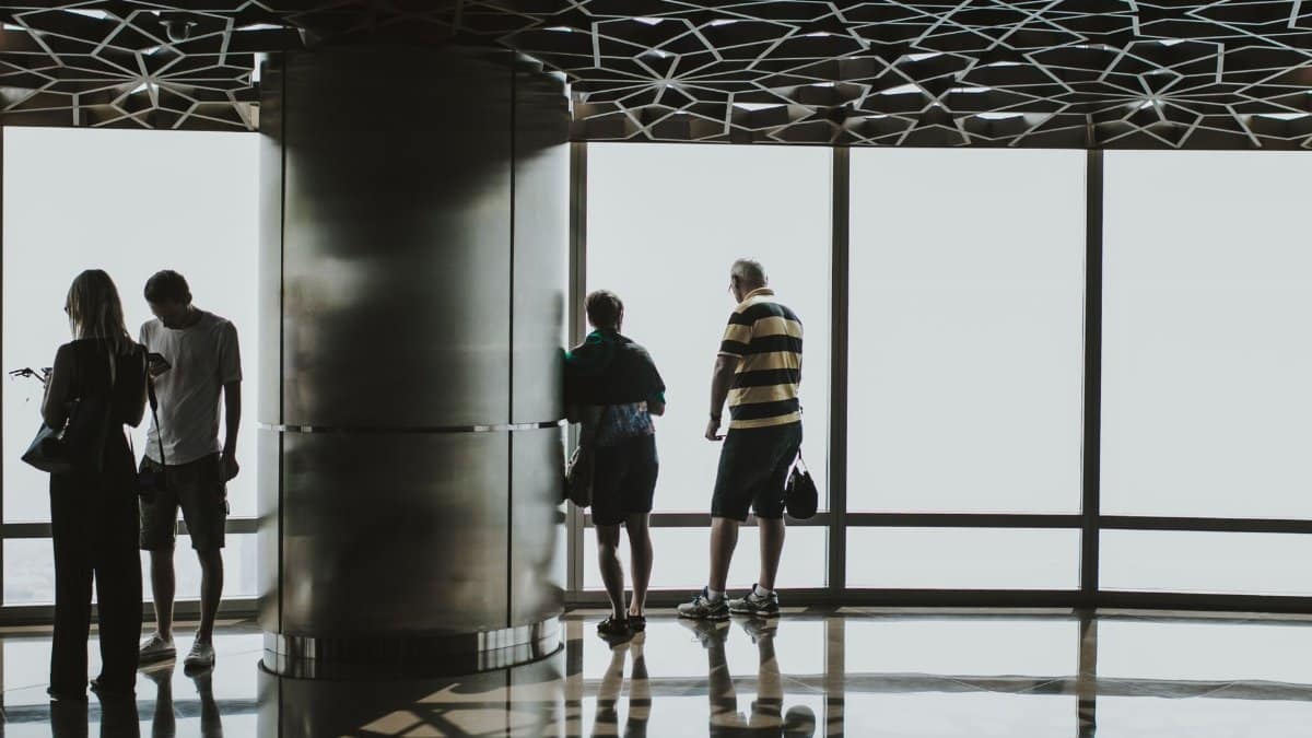 Four people observing a panoramic view from a modern high-rise in Dubai.