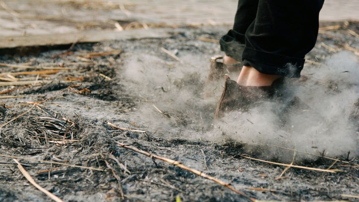 Feet walking on ashy ground with smoke rising, showcasing outdoors and mystery.