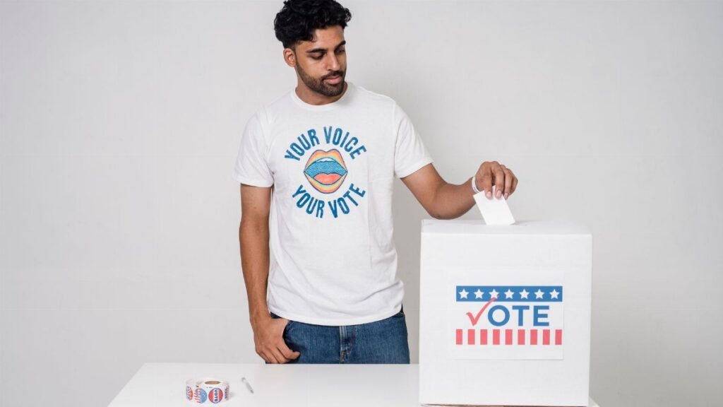 Young man casting a vote into a ballot box on a white background promoting democracy.