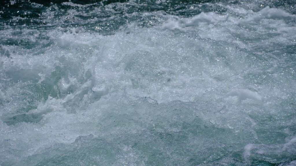 Close-up view of a rushing river with turbulent water showcasing rapid motion and fluidity.