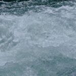 Close-up view of a rushing river with turbulent water showcasing rapid motion and fluidity.