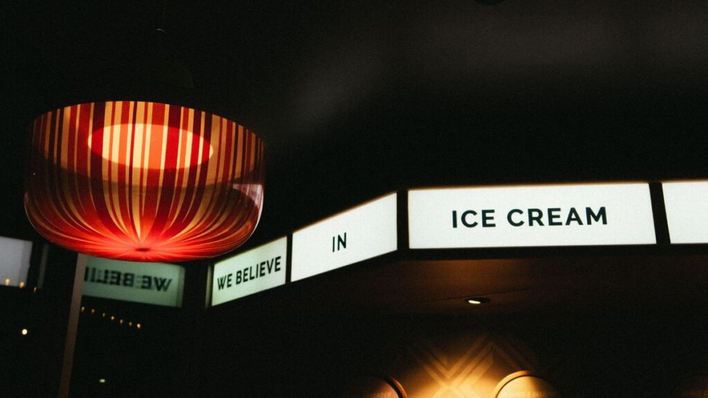 Warm indoor setting featuring a glowing lamp and 'We Believe in Ice Cream' sign.