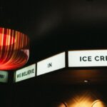Warm indoor setting featuring a glowing lamp and 'We Believe in Ice Cream' sign.