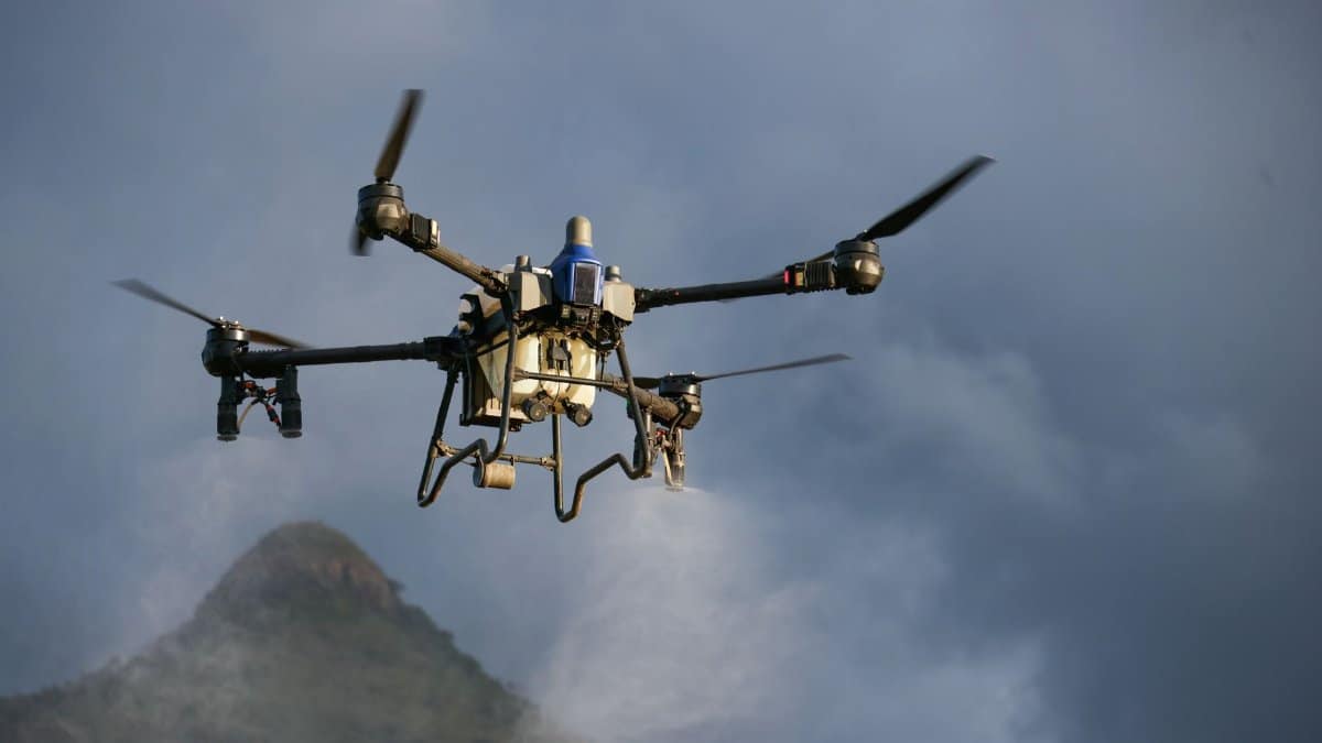 Close-up of a drone mid-flight against a cloudy mountain backdrop, showcasing modern aerial technology.