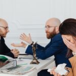 A lawyer mediates an emotional settlement discussion with a distressed couple in a legal office.