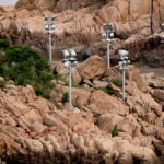 Multiple surveillance cameras monitor a rocky coastline with surrounding vegetation.