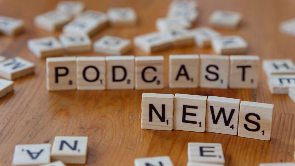 Wooden letter tiles spelling out 'PODCAST NEWS' on a wooden surface.