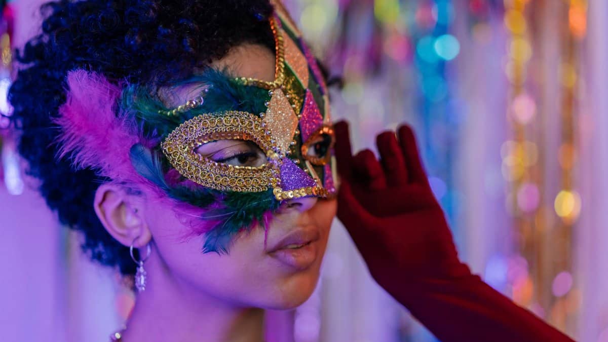 Vibrant masquerade mask with feathers worn at an indoor festive celebration.