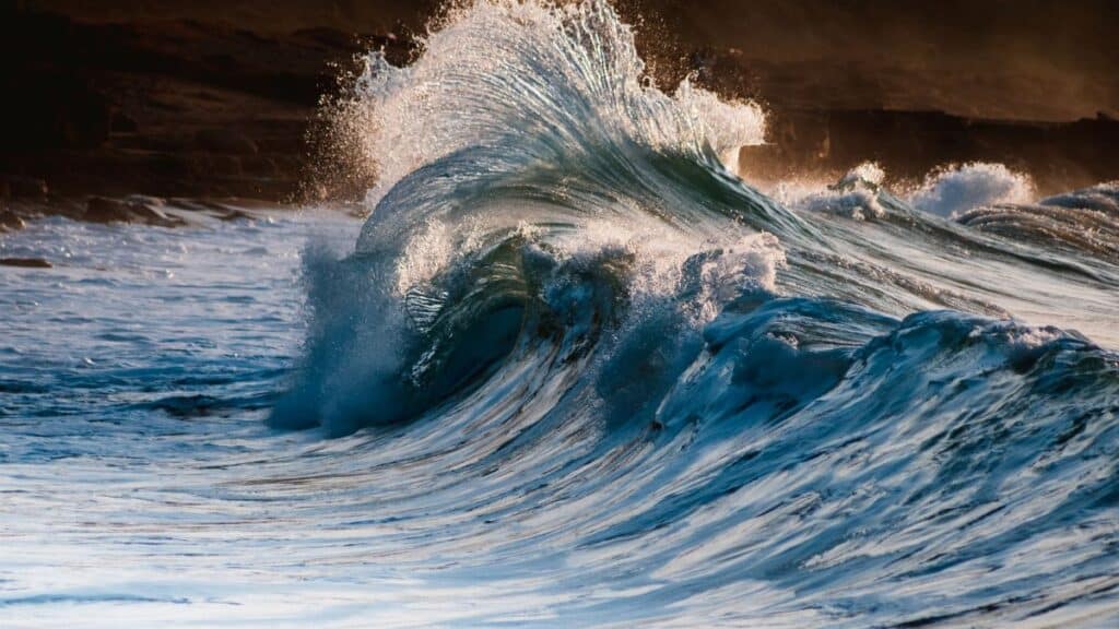 Powerful waves crashing on rocky shoreline at sunrise, capturing the beauty and force of the sea.
