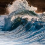 Powerful waves crashing on rocky shoreline at sunrise, capturing the beauty and force of the sea.