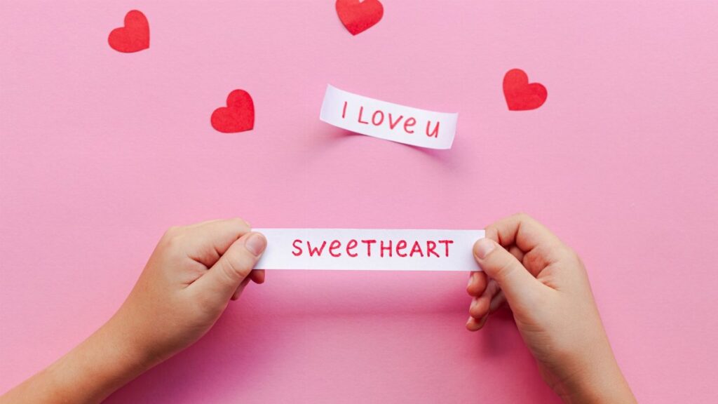 Hands holding love notes on pink background with red hearts. Perfect for Valentine's Day.