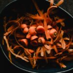 Close-up photo of fresh carrot peels and scraps in a dark bowl, perfect for food waste or preparation themes.