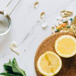 Flat lay of lemon, ginger, and supplements on a marble surface, illustrating natural remedies.