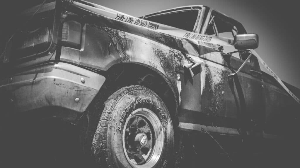 Dramatic black and white image of a damaged truck with police tape.