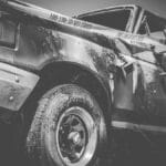 Dramatic black and white image of a damaged truck with police tape.