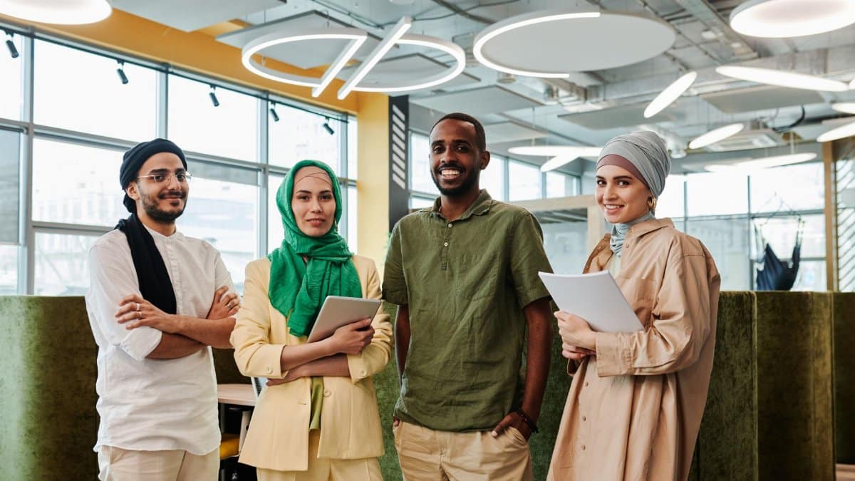 Diverse group of professionals posing confidently in a modern office setting, showcasing teamwork.