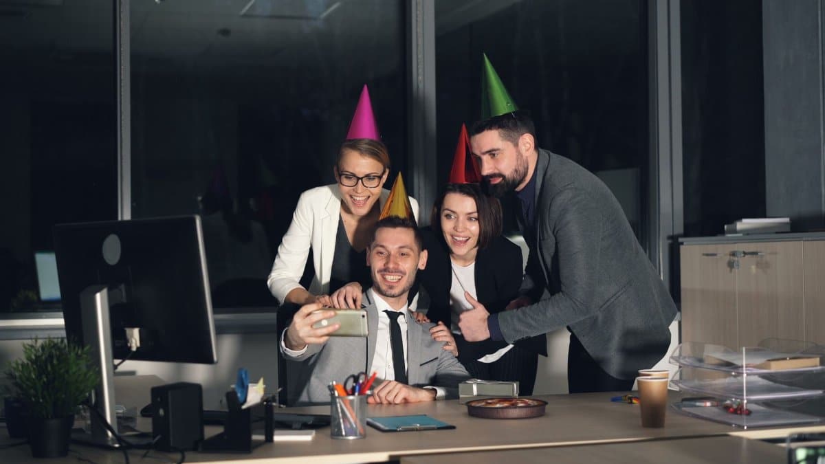 Joyful office celebration with coworkers taking a selfie during late-night party.