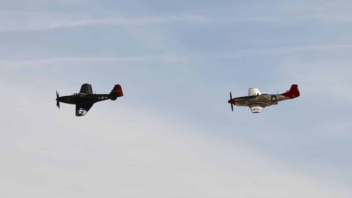 Two vintage World War II aircraft flying at March Air Reserve Base, showcasing historical aviation.