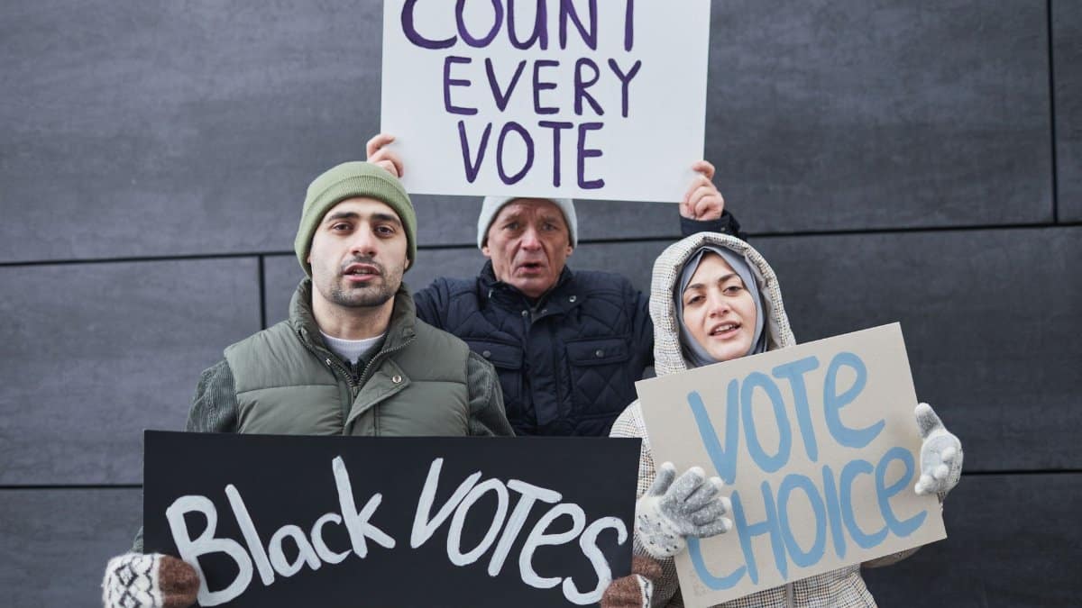 A diverse group of people holding signs advocating for voting rights and equality during a winter outdoor protest.