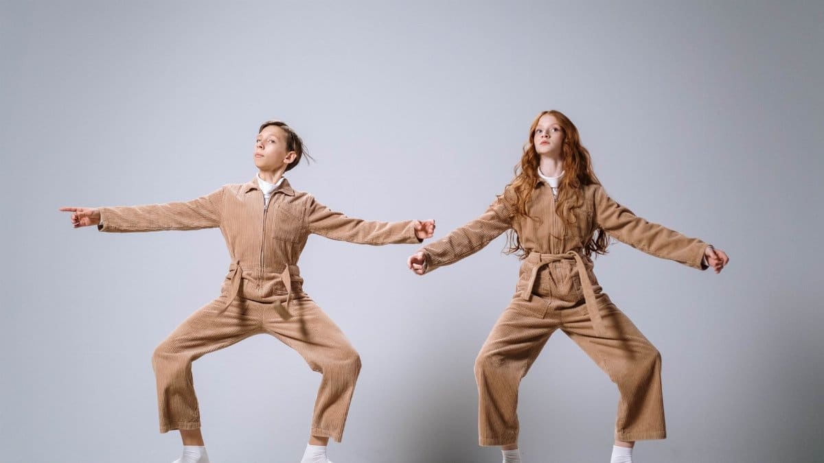 Two teens in coordinated outfits striking a creative pose in a studio setting.