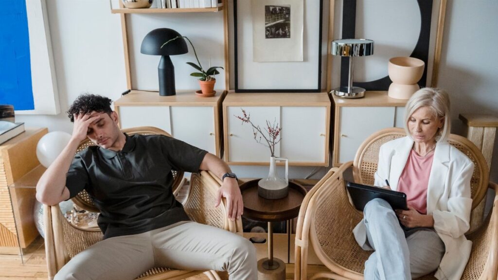 A stressed man and woman therapist in a modern consultation room.