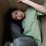 Woman enclosed in a cardboard box, showing signs of stress and fear.