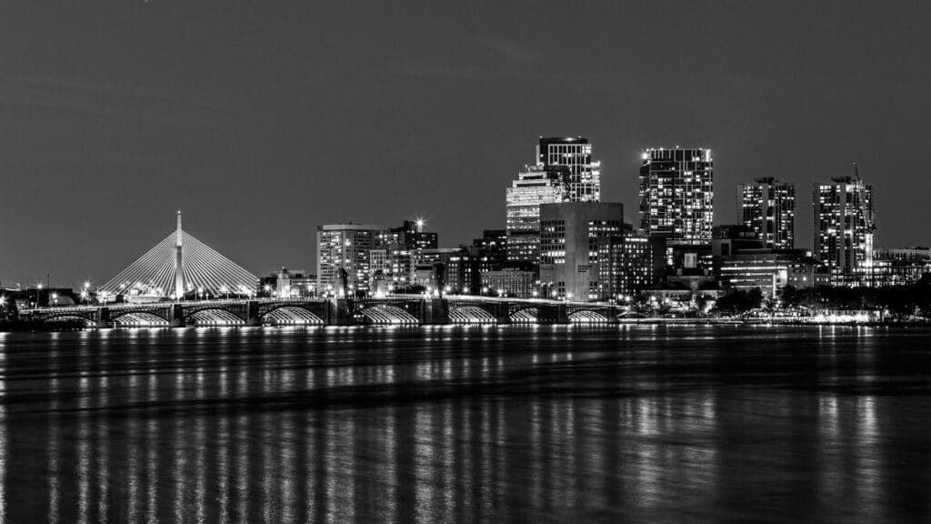 Elegant black and white night view of Boston's illuminated city skyline over Charles River.